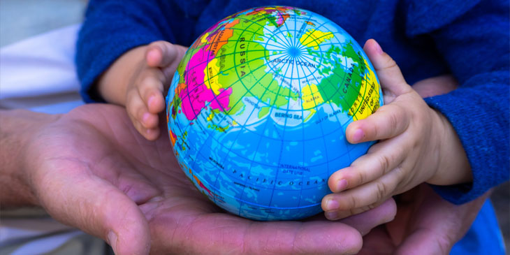 Close-up of the hands of a young child and an adult holding a globe