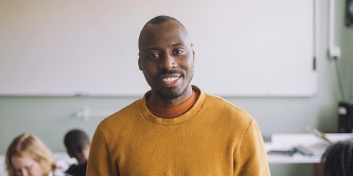 Image of teacher smiling in his classroom