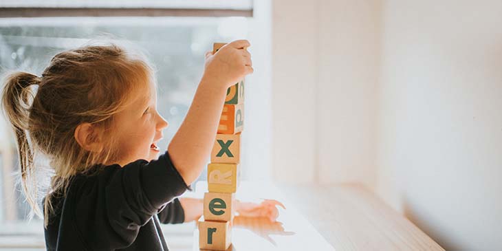 Little girl building a tower with wooden blocks