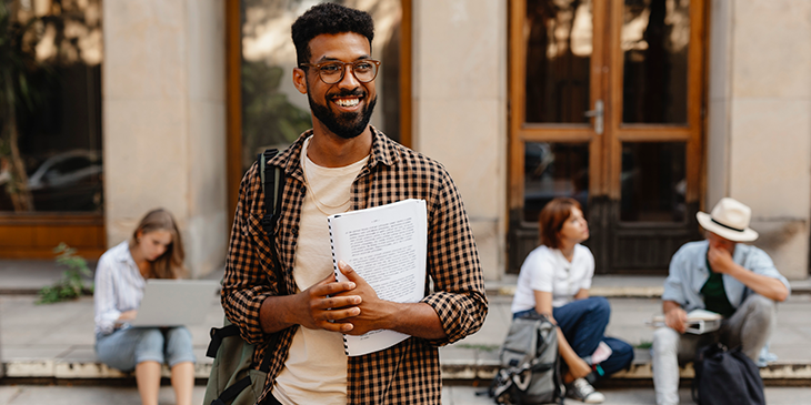 A smiling University student holding some books