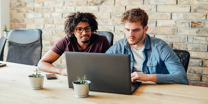 two colleagues looking at the same laptop screen