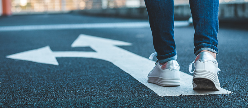 stock image of person walking on road with painted arrow