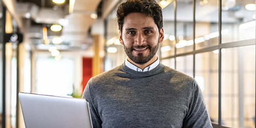 Man smiling holding a laptop
