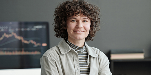Woman smiling at camera in front of a monitor