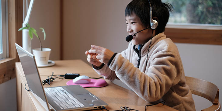young student smiling wearing a headset and looking at laptop
