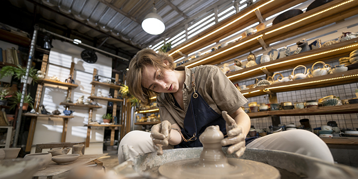 Young woman molding clay on pottery wheel workshop at the ceramic shop