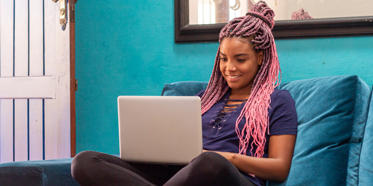 a teenage student sitting down working with a laptop on their lap 