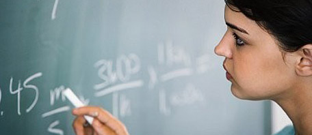 Female student writing maths on a chalk board