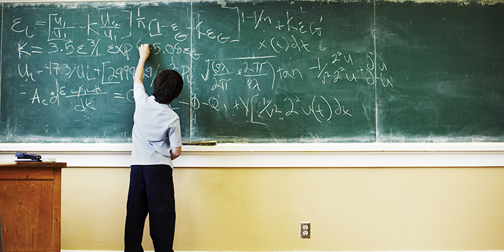 Boy solving complex equation on a blackboard