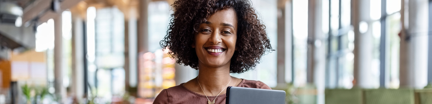 Woman smiling at camera holding a laptop