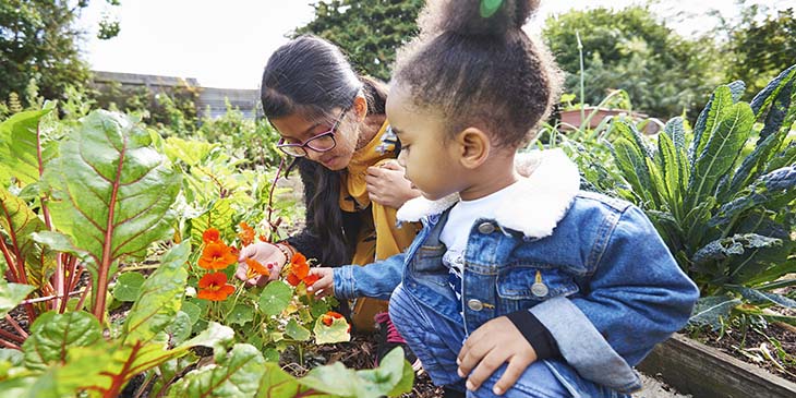 two young girls looking at flowers in a garden