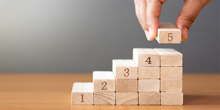 a hand placing numbered wooden blocks in ascending order