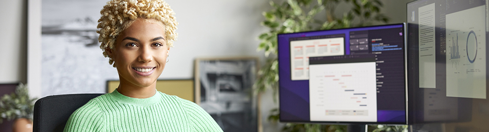 Woman smiling with computer monitors in background