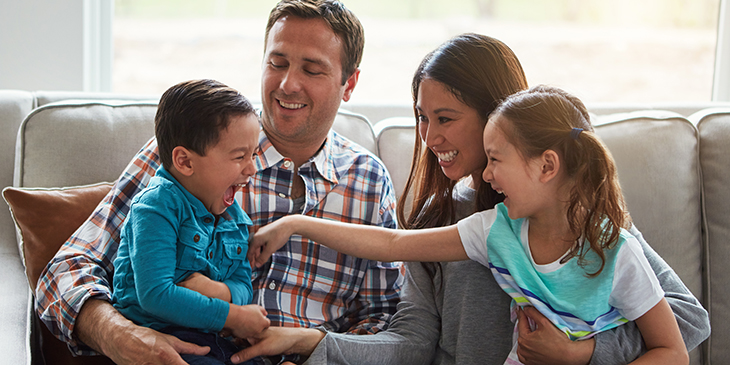 Photograph of a family with two children laughing