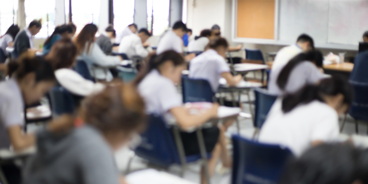 view from the back of a hall of students taking an exam