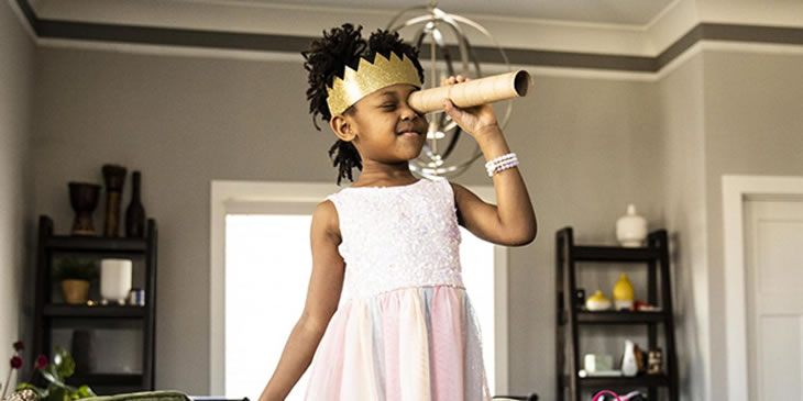 young girl wearing a toy crown looking through a homemade telescope