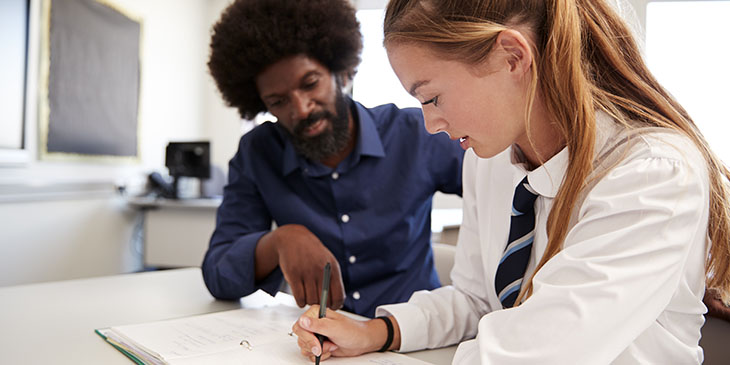 teacher helping secondary school student in class