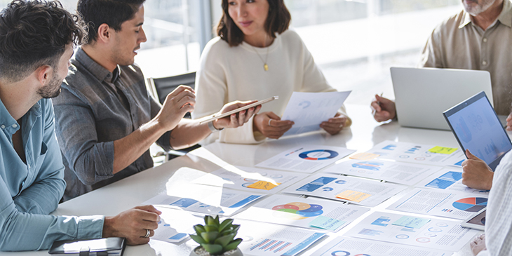 Group of professionals at a board room table looking at research documents